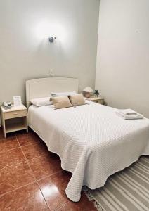 塔里哈Hotel Renacer Tarija的卧室配有一张带两张桌子的大型白色床