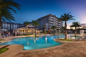 希尔顿黑德岛Hilton Grand Vacations Club Ocean Oak Resort Hilton Head的一座棕榈树度假村游泳池和一座建筑
