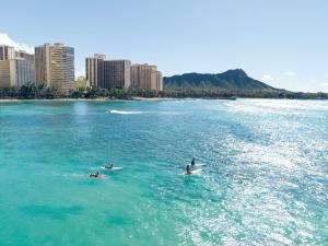 檀香山Embassy Suites by Hilton Waikiki Beach Walk的两人在城市附近的水面冲浪板上