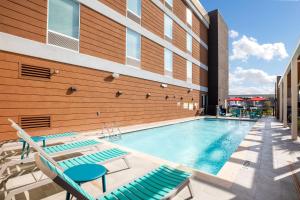 休斯顿Home2 Suites by Hilton Houston Bush Intercontinental Airport Iah Beltway 8的一座带躺椅的游泳池,位于大楼旁