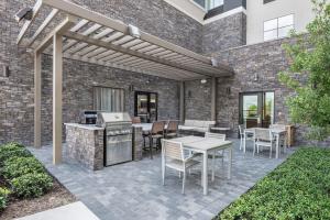 休斯顿Homewood Suites By Hilton Houston Memorial的一个带烧烤架和桌椅的庭院