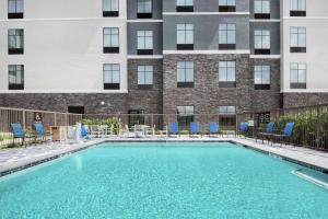 休斯顿Homewood Suites By Hilton Houston Memorial的一座带蓝色椅子的游泳池和一座建筑
