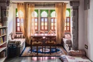 乌代浦拉西旅馆的客房设有桌子、两把椅子和窗户。