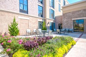 里奇兰Hampton Inn & Suites Ridgeland的一座建筑前带椅子和鲜花的庭院