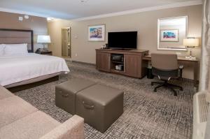 里奇兰Hampton Inn & Suites Ridgeland的酒店客房配有一张床、一张书桌和一台电视。