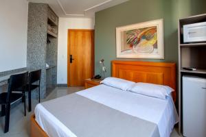 贝洛奥里藏特Savassinho Hotel & Residence的卧室配有白色的床和电视。