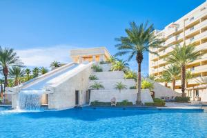 拉斯维加斯Hilton Vacation Club Cancun Resort Las Vegas的一座拥有瀑布的建筑,毗邻一个棕榈树游泳池