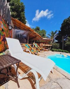 帕尔梅拉斯Recanto Villa São João的游泳池旁的白色躺椅