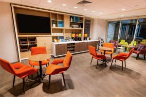 拉斯维加斯Home2 Suites by Hilton Las Vegas Stadium District的一间配备有橙色椅子和平面电视的等候室