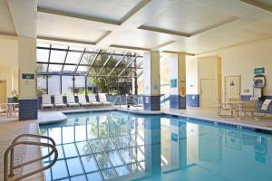 洛杉矶洛杉矶国际机场北使馆套房酒店的大楼内一个带桌椅的游泳池