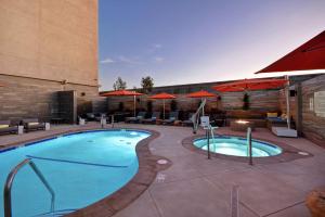 伯班克洛杉矶伯班克机场汉普顿套房酒店的一个带桌子和遮阳伞的酒店游泳池