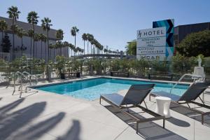 洛杉矶洛杉矶国际机场希尔顿惠庭套房酒店的一座带两把椅子的游泳池位于大楼旁
