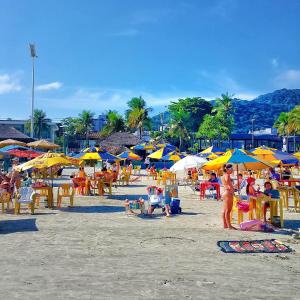 瓜鲁雅Dom Pedro 26的一群人坐在海滩上,拿着遮阳伞