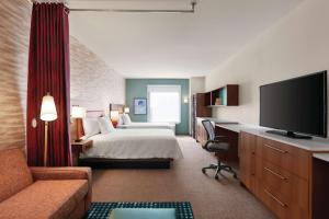兰开斯特Home2 Suites By Hilton Lancaster的酒店客房配有一张床和一张书桌及一台电视