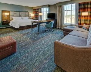 孟菲斯Hampton Inn & Suites Memphis Germantown的酒店客房配有床、沙发和桌子。