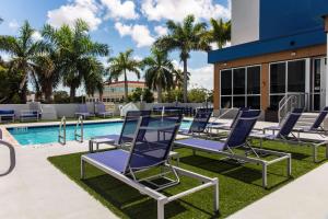 迈阿密汗姆顿酒店迈阿密机场南/蓝礁湖的一组躺椅,位于游泳池旁