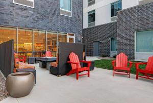 密尔沃基Tru By Hilton Milwaukee Downtown, WI的大楼前方的带红色桌椅的庭院