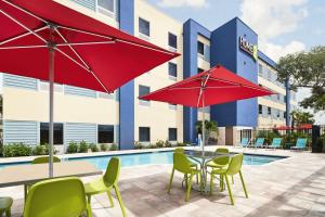 墨尔本Home2 Suites By Hilton Palm Bay I 95的游泳池旁的天井配有桌椅和遮阳伞。
