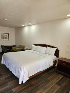 图克姆卡里Rodeway Inn的卧室配有一张白色大床和一把椅子