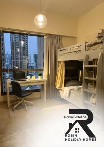 迪拜Robin Beach Hostel JBR的一间卧室配有双层床、书桌和窗户。