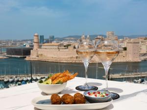 马赛索菲特马赛老港口酒店的两杯酒和一盘桌上的食物