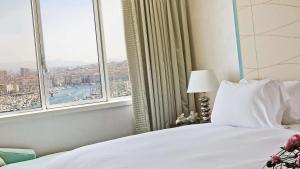 马赛索菲特马赛老港口酒店的一间卧室设有一张床和一个大窗户