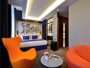第戎Grand Hotel La Cloche Dijon - MGallery的酒店客房,配有床和橙色椅子