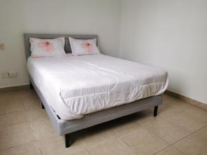 巴拿马城Apartment in the City的床上铺有白色床单和粉红色枕头
