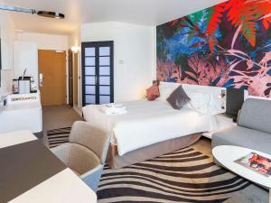 卢森堡卢森堡中心诺富特酒店的卧室配有一张床,墙上挂有绘画作品