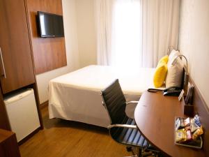 南圣卡埃塔诺圣卡埃塔诺美居酒店的酒店客房配有书桌、床和桌子。