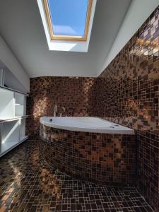 普里兹伦Nam Hotel的带浴缸的浴室和天窗