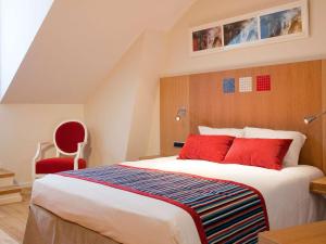 维泰勒维泰勒美居酒店的一间卧室配有一张大床和一张红色椅子
