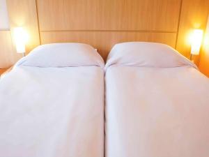 欧里尼奥斯ibis Ourinhos的配有白色床单的酒店客房内的两张床