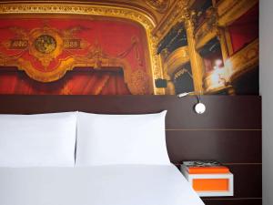 蒙彼利埃蒙彼利埃喜剧中心宜必思尚品酒店的卧室配有一张床,墙上挂有绘画作品
