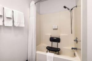 迪波湾Travelodge by Wyndham Depoe Bay的带淋浴和黑色凳子浴缸的浴室