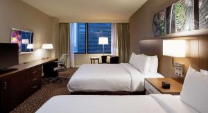 达拉斯达拉斯市中心希尔顿花园酒店的酒店客房设有两张床、一张桌子和一台电视。