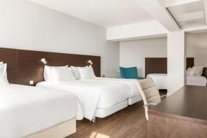 阿姆斯特丹阿姆斯特丹市中心NH酒店的酒店客房带两张床和一张桌子以及椅子。