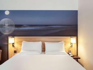斯丹斯达蒙费雪特伦敦斯坦斯特德机场诺富特酒店的一间卧室配有一张壁画床