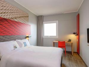 特鲁希略ibis Trujillo的酒店客房设有一张大床和一张红色椅子。
