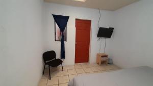 危地马拉Hotel Bluehouse的一间设有床铺、红色门和椅子的房间