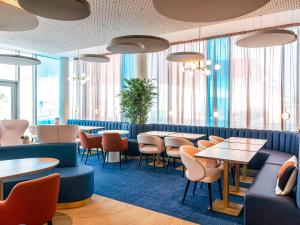 敦刻尔克Mercure Dunkerque Centre Gare的餐厅设有桌椅和窗户。