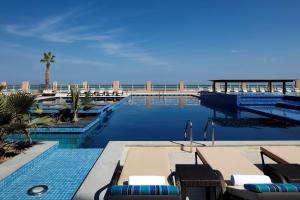 索哈尔Radisson Blu Hotel & Resort, Sohar的毗邻大海的带桌椅的游泳池