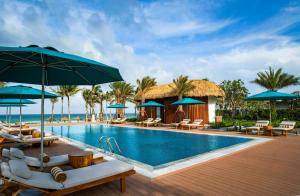 金兰Radisson Blu Resort Cam Ranh的度假村的游泳池,配有椅子和遮阳伞