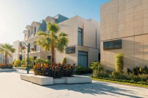 利雅德Mansard Riyadh, a Radisson Collection Hotel的前面有棕榈树的建筑