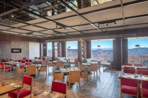 西姆拉Radisson Kufri的餐厅配有桌椅,位于山脉的背景中。