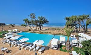 塔哈佐特Radisson Blu Resort Taghazout Bay Surf Village的一个带躺椅的游泳池和海滩