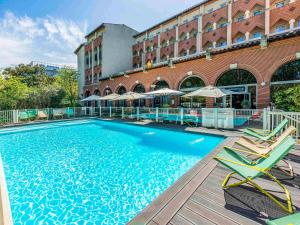 图卢兹图卢兹中心康格诺富特酒店的一座带椅子的大型游泳池和一座建筑