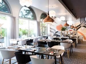 图卢兹图卢兹中心康格诺富特酒店的用餐室设有桌椅和窗户。