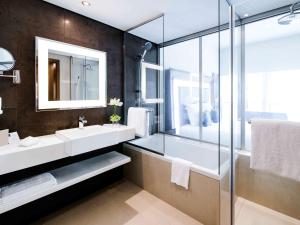 富查伊拉诺富特富查伊拉酒店的一间带两个水槽和玻璃淋浴间的浴室