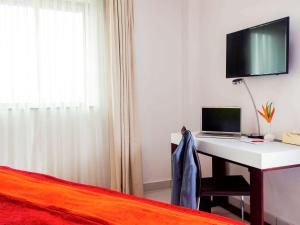 阿克拉阿克拉机场宜必思尚品酒店的一间卧室配有一张桌子、一台笔记本电脑和一张床